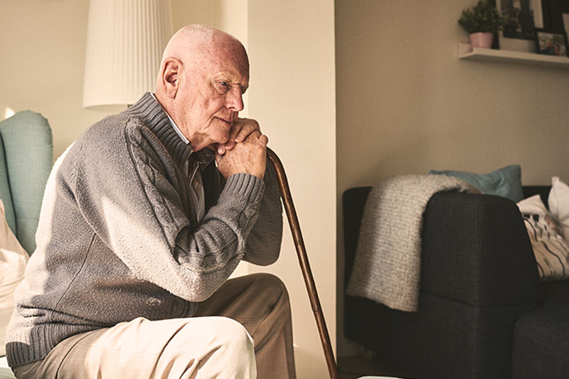 sad-senior-man-leaning-on-cane