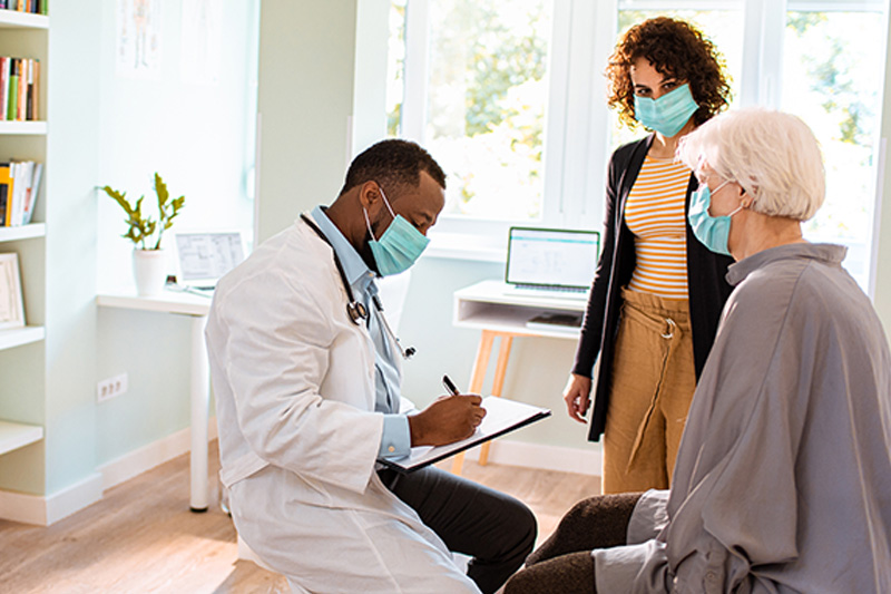 Doctor talking with senior woman and her family caregiver