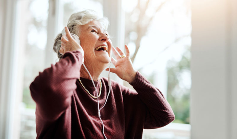 gleeful senior woman wearing headphones